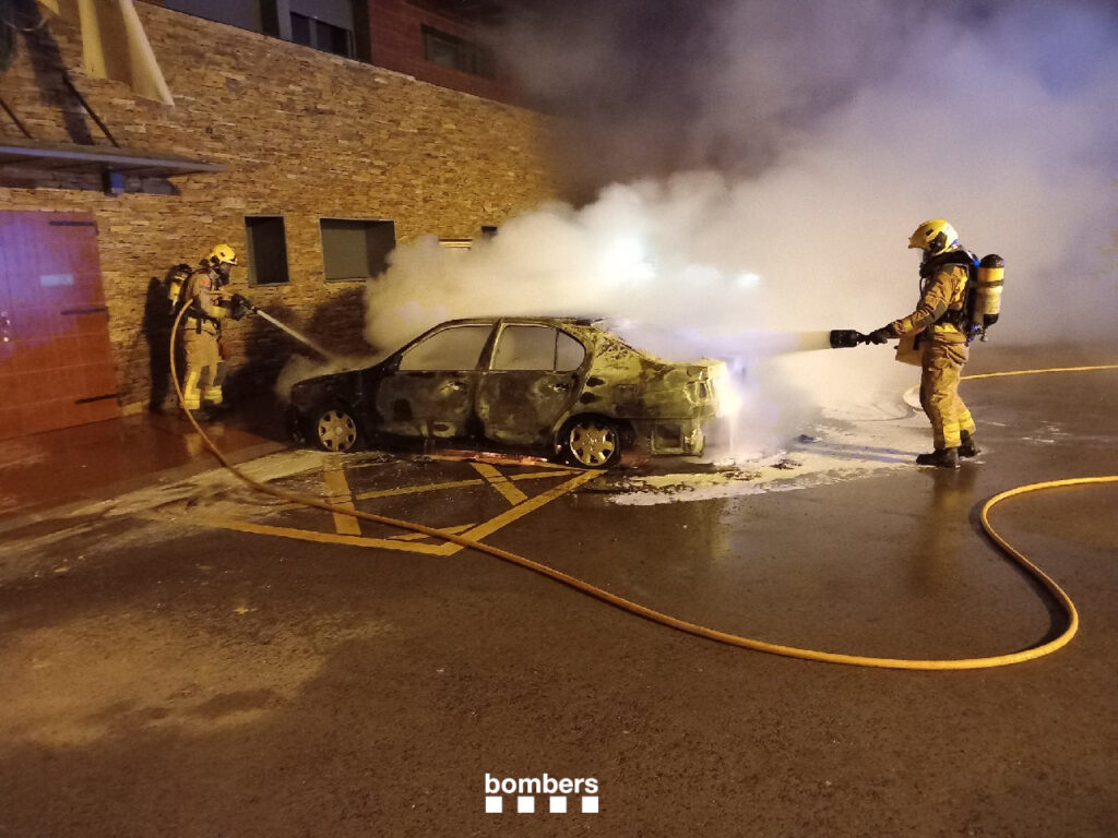 Dos bombers apaguen un dels cotxes cremats a Montferrer. Foto: Bombers.