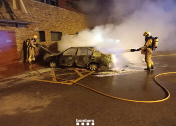 Dos bombers apaguen un dels cotxes cremats a Montferrer. Foto: Bombers.