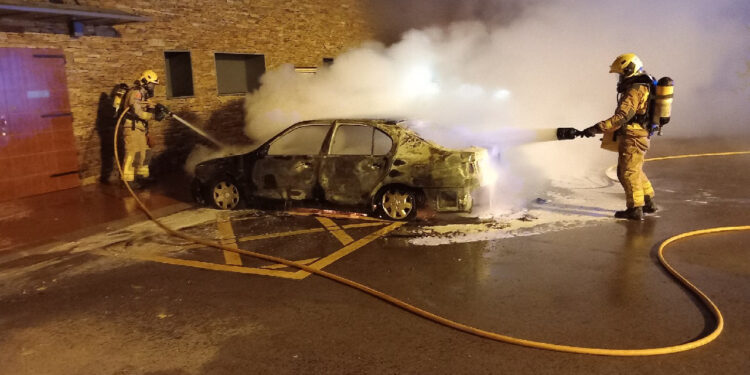 Dos bombers apaguen un dels cotxes cremats a Montferrer. Foto: Bombers.
