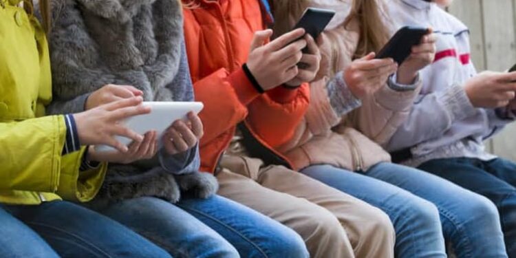 Un grup de nens fan servir el mòbil i les xarxes socials al carrer (Foto: Xarxes).