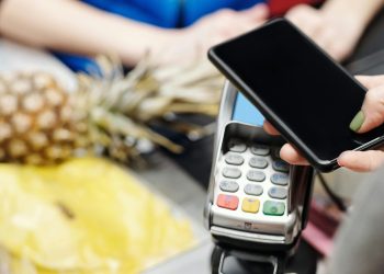 Una noia pagant una compra amb el seu telèfon mòbil. Foto: Pexels