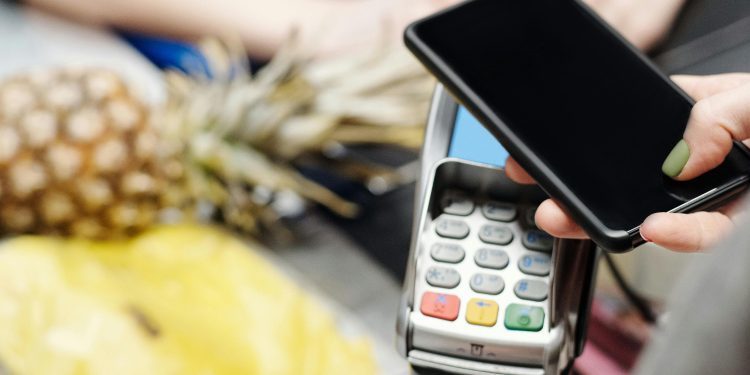 Una noia pagant una compra amb el seu telèfon mòbil. Foto: Pexels