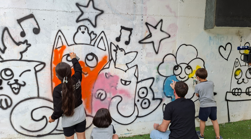 Els nens i nenes de l'escola d'art pintant el tram de mur habilitat.
