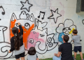 Els nens i nenes de l'escola d'art pintant el tram de mur habilitat.