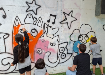 Els nens i nenes de l'escola d'art pintant el tram de mur habilitat.