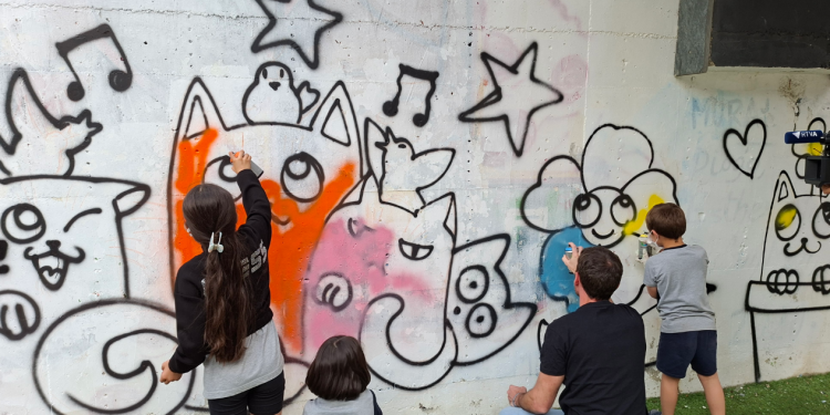 Els nens i nenes de l'escola d'art pintant el tram de mur habilitat.