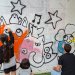 Els nens i nenes de l'escola d'art pintant el tram de mur habilitat.