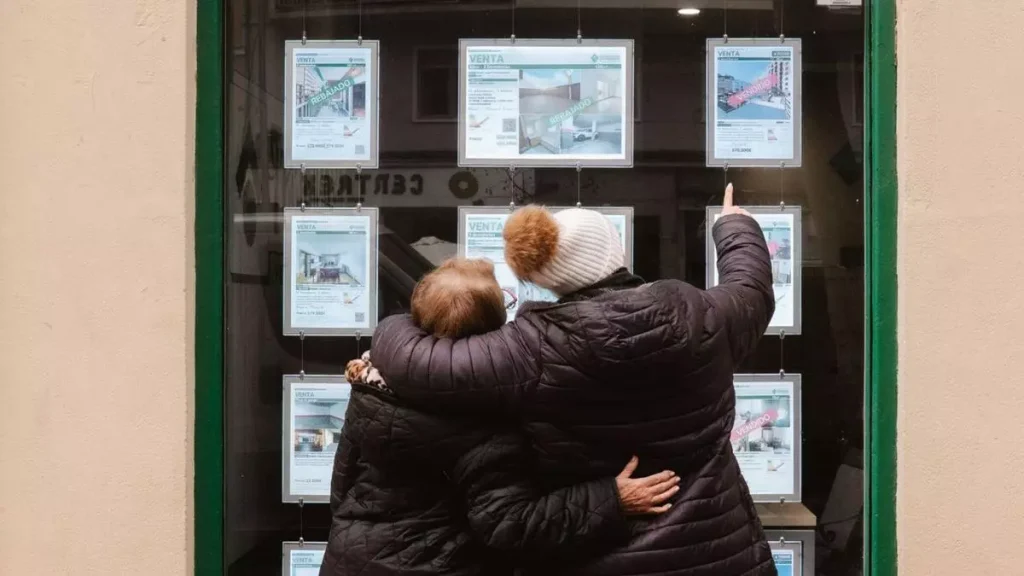 Dues dones miren anuncis en l'aparador d'una immobiliària / KT